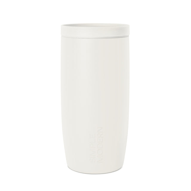 Cream-colored cylindrical travel mug with tapered design and embossed SM logo, shown against white background in studio product photography. Cream-colored cylindrical travel mug with tapered design and embossed SM logo, shown against white background in studio product photography.