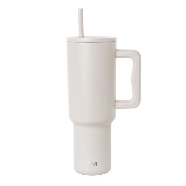 Cream-colored insulated tumbler with handle and matching lid featuring a centered straw. Simple Modern logo embossed on lower front. Cylindrical design with wider top tapering to narrow base on white background. Cream-colored insulated tumbler with handle and matching lid featuring a centered straw. Simple Modern logo embossed on lower front. Cylindrical design with wider top tapering to narrow base on white background.