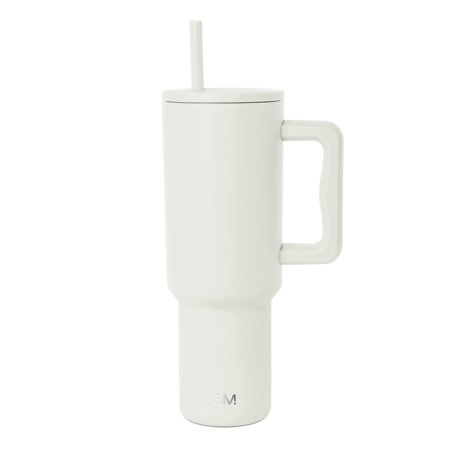 Cream insulated tumbler with handle and straw, shown against white background. Tall cylindrical design with tapered base, large squared handle, fitted lid, and straight straw. SM logo visible on front. Cream insulated tumbler with handle and straw, shown against white background. Tall cylindrical design with tapered base, large squared handle, fitted lid, and straight straw. SM logo visible on front.