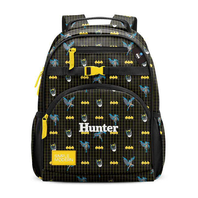 Batman-themed children's backpack with yellow bat symbols and logos on black ripstop nylon, featuring yellow accents, multiple pockets, padded handles, and 