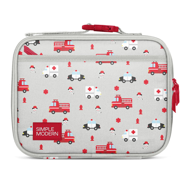 Gray insulated lunch box with emergency vehicle pattern featuring red fire trucks, ambulances, police cars, and fire hydrants. Red zip closure and side pockets. Simple Modern brand label on front.