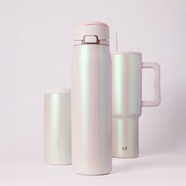 Iridescent pearlescent cosmetic products in pale pink, cream, and white with subtle color-shifting finish between blush pink and mint green tones.