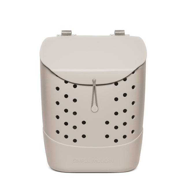 Beige minimalist backpack with black perforated circular pattern, silver textured handles, gray cord pull, and 