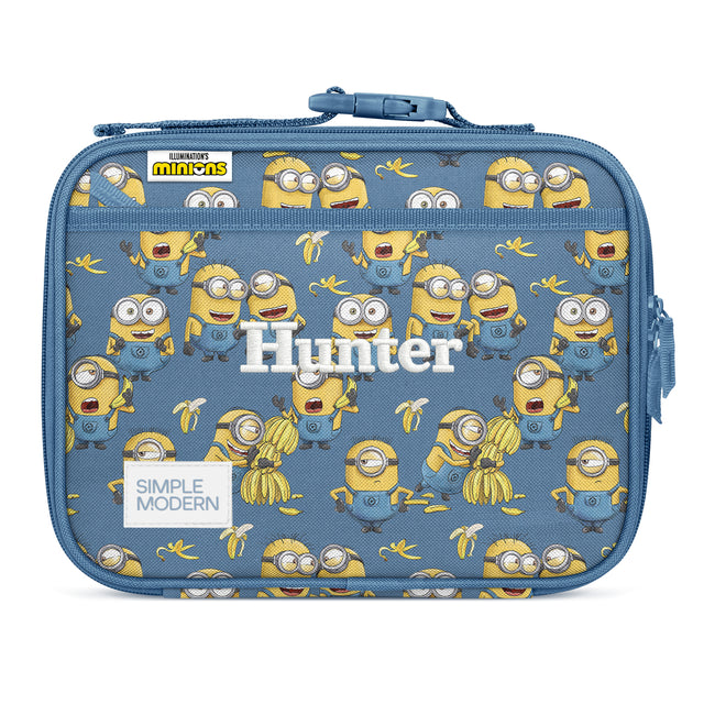 Slate blue Simple Modern insulated lunch box with repeating Minions characters in yellow and blue, featuring a blue zippered closure, shoulder strap, and personalized 