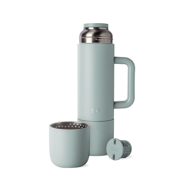 Sage green insulated thermos with matching cap and cup, displayed with handle and accessories against white background
