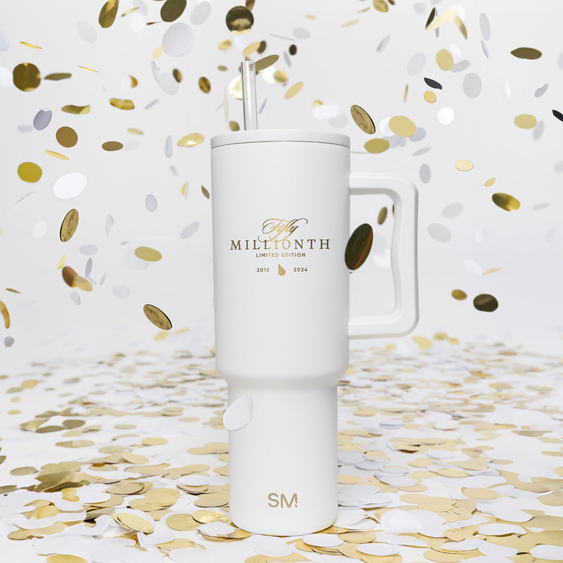 Commemorative Dyson Supersonic hair dryer in white and gold metallic finish with celebratory confetti, marking the 50 millionth product milestone.