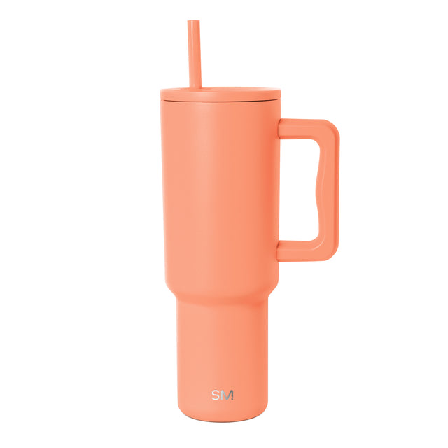Coral pink insulated tumbler by Simple Modern with matching handle and integrated straw, shown against white background with SM logo visible on front.