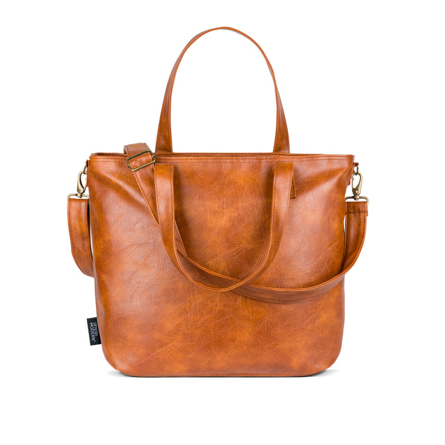 Cognac brown leather handbag with golden undertones against white background