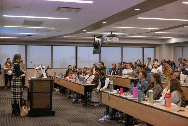 A speaker addressing Simple Modern employees seated at long tables during the company's annual Giving Summit
