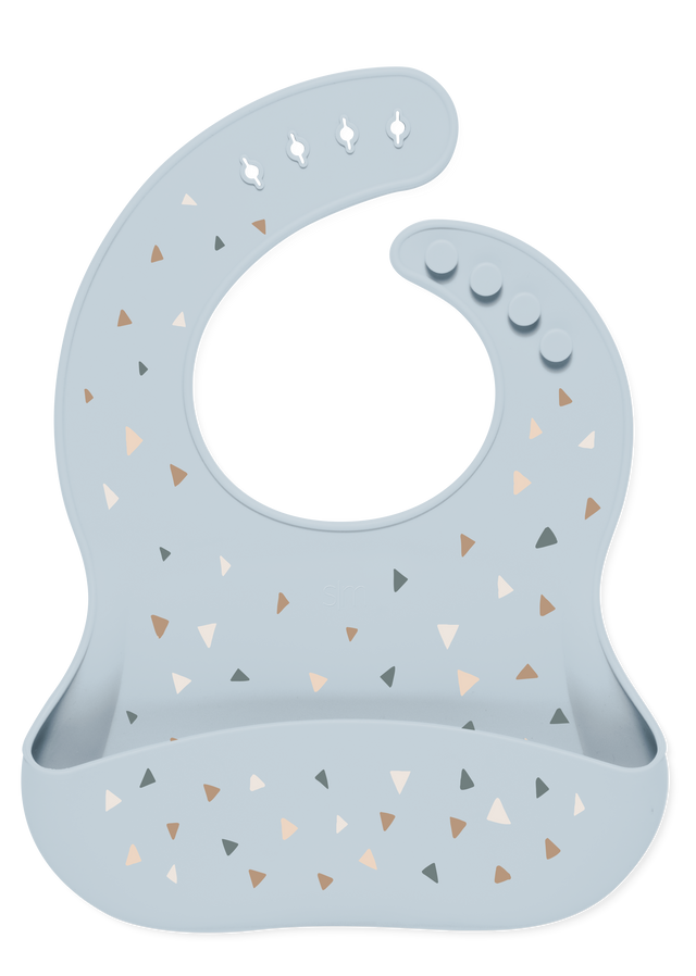 Light blue-gray baby bib with decorative triangular accents in tan, beige, caramel brown, and charcoal gray.